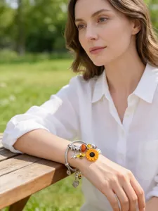 Primo piano del bracciale in acciaio con ciondoli girasole e ape sul polso