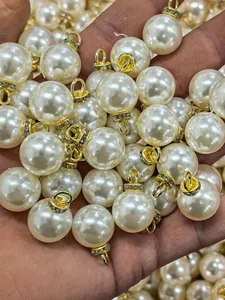 Close-up of white ABS imitation pearl charms with gold jump rings and rhinestones.