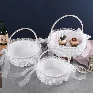 Detailed view of three white ruffled lace wedding flower baskets with satin ribbons.
