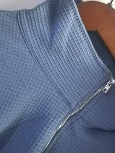 Close-up macro view showing the blue waffle-knit fabric texture and metal zipper detail