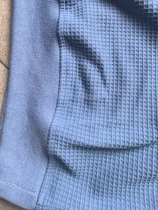 Macro view of blue waffle-knit texture and ribbed cuff details on a men's sweatshirt