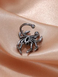 Detailaufnahme einer Gothic-Spinne-Ohrklemme aus Gunmetal auf champagnerfarbenem Seidenstoff