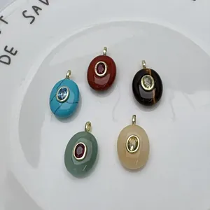 Vue détaillée de cinq pendentifs ovales en pierre naturelle avec un zircon incrusté.