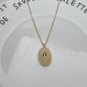 Gros plan d'un élégant pendentif ovale en pierre naturelle avec zircon au centre.