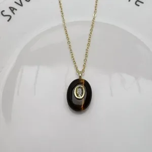 Détail d'un pendentif ovale élégant en pierre naturelle avec zircon sur chaîne d'or.