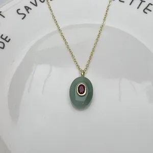 Détail d'un pendentif ovale en pierre verte naturelle avec zircon rouge et chaîne