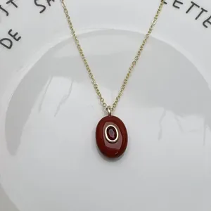 Détail d'un collier avec pendentif ovale en pierre naturelle rouge et chaîne en or