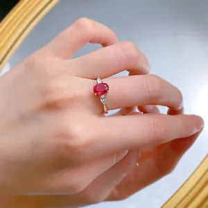 Primer plano detallado de un anillo de plata S925 con corindón rojo óvalo en el dedo
