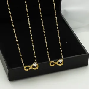 Two gold infinity necklaces with crystal accents displayed in a black luxury gift box