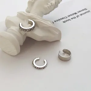 Close-up of minimalist silver-tone C-shaped ear cuffs with sparkling rhinestone details