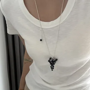 Detailed view of a long adjustable silver necklace with a black crystal grape pendant