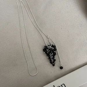 Detailed shot of an adjustable long necklace featuring a black crystal grape cluster.