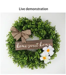 Detailed view of an artificial green boxwood wreath with home sweet home wooden sign and bow
