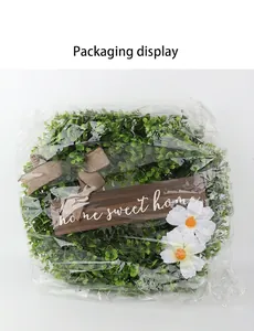 Artificial green boxwood wreath with home sweet home sign in clear plastic packaging