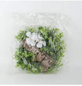 Macro view of artificial Christmas wreath with Welcome sign inside packaging