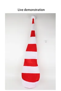Long red and white striped Christmas elf hat shown hanging on a white wall