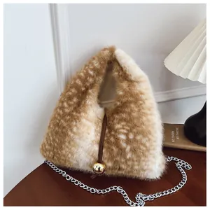 Detailansicht einer flauschigen Tasche mit Fleckenmuster, Goldanhänger und Silberkette.