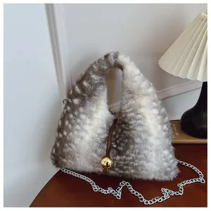 Detailansicht einer gepunkteten Pelzhandtasche mit Silberkette und Goldkugel