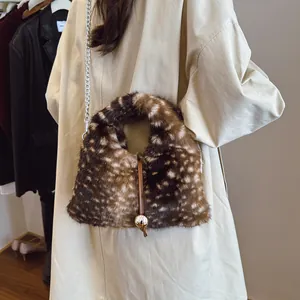 Handtasche aus Kunstpelz mit Hirschmuster und goldener Hardware auf beigem Mantel