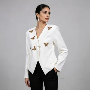 Detailed view of white slim-fit blazer featuring ornate gold bee embellishments