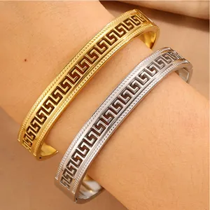 Detail view of gold and silver stainless steel bangles with intricate Greek key pattern
