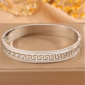 Macro detail of a silver titanium steel bangle featuring an elegant Greek key pattern.