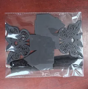 Detailed view of flat-packed black laser-cut butterfly favor boxes with ribbons