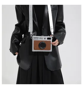 Detail shot of a vintage camera-shaped box bag with silver strap and brown leather texture
