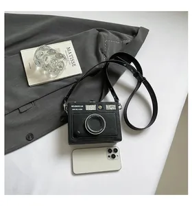 Detailed top view of a vintage camera-shaped crossbody bag with a smartphone for size comparison.