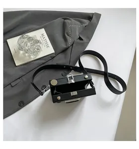 Top view of an open retro black camera-shaped box bag featuring sleek silver hardware