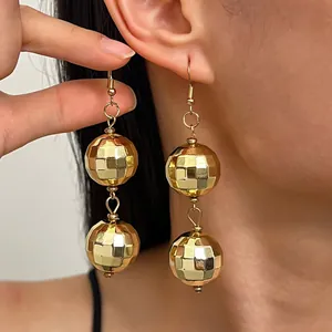 Primo piano di orecchini vintage a sfera disco dorata indossati all'orecchio per stile