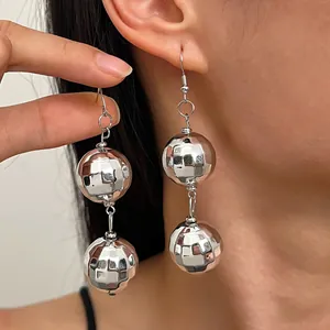 Dettaglio di orecchini a palla disco d'argento con sfaccettature riflettenti e lucentezza.