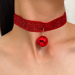 Vista dettagliata del girocollo rosso glitterato con un lucente ciondolo a palla da discoteca