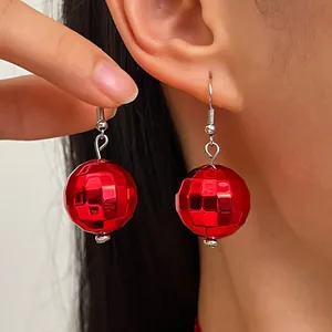 Dettaglio macro di orecchini a palla da discoteca rosso vivace con finitura lucida