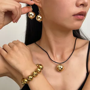 Dettaglio di un set di gioielli a sfera disco d'oro con orecchini, collana e bracciale