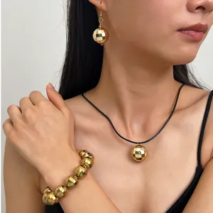 Modella indossa un set di gioielli a sfera disco dorata con collana, orecchini e bracciale