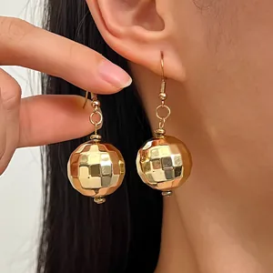 Primo piano di orecchini a palla da discoteca dorati con dettagli superficiali sfaccettati