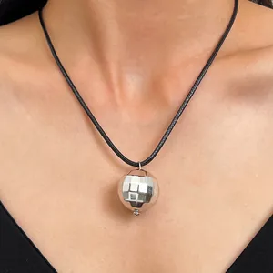 Dettaglio ravvicinato di una collana con ciondolo a sfera da discoteca argento e nero.
