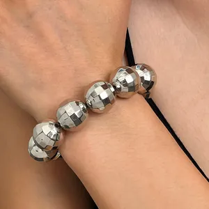 Vista dettagliata di un braccialetto di perline disco ball argento su un polso femminile.