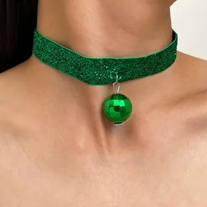 Primo piano di una collana choker verde glitterata con un pendente a forma di disco ball.