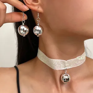 Vista dettagliata di una donna con orecchini a palla da discoteca e collana choker.