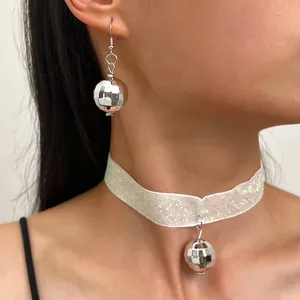 Dettaglio ravvicinato di orecchini a palla da discoteca e choker iridescente coordinato