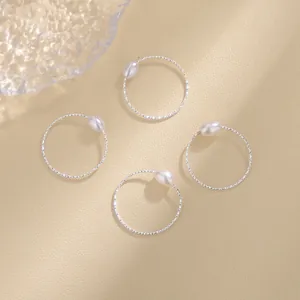 Detailansicht von vier minimalistischen Silberringen mit eleganten weißen Muschelperlen.