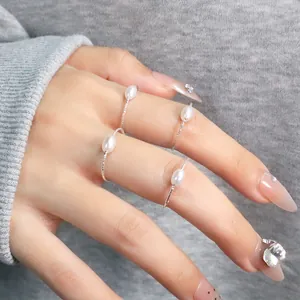 Detailansicht von vier silbernen Ringen mit ovalen Muschelperlen auf der Hand