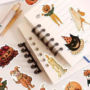 Close-up of vintage Halloween stickers featuring pumpkin and black cat designs on a notebook
