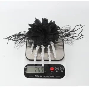 Detailed view of Halloween skeleton hand and black flower hair clip weighing 26.5g on scale.