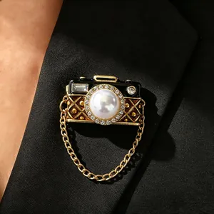 Elegante vintage camera-broche met een grote parel en kristallen op een blazer