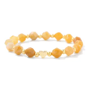 Detailed view of faceted yellow stone beads and polished gold heart charm