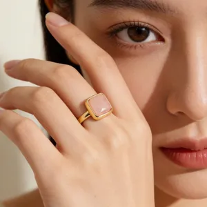 Close-up of a square pink crystal ring on an elegant hand with a minimalist gold band