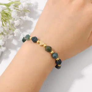 Close-up of elegant faceted stone bead bracelet with a polished gold heart charm on wrist